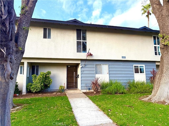 multi unit property with a front yard and stucco siding