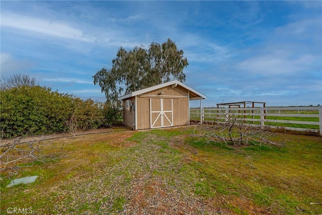 view of outdoor structure featuring a rural view and a lawn