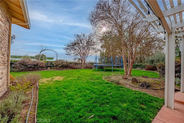 view of yard featuring a trampoline and a pergola