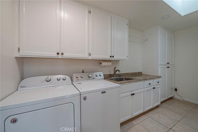 washroom featuring light tile patterned floors, a skylight, sink, washer and dryer, and cabinets