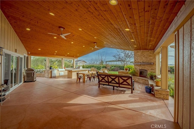 view of patio featuring area for grilling, ceiling fan, and an outdoor living space with a fireplace