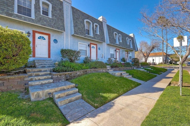 view of front facade featuring entry steps, a front lawn, mansard roof, and roof with shingles