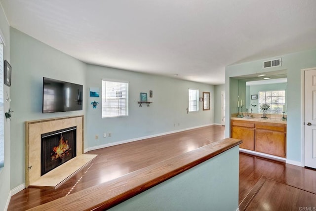 kitchen with a sink, visible vents, a high end fireplace, light countertops, and dark wood finished floors