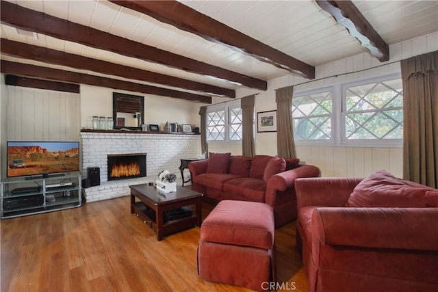 living room featuring a fireplace, beamed ceiling, plenty of natural light, and light hardwood / wood-style flooring