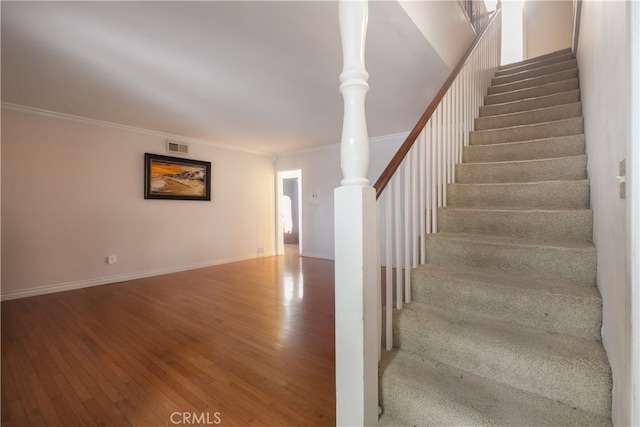 stairway featuring ornamental molding and wood-type flooring