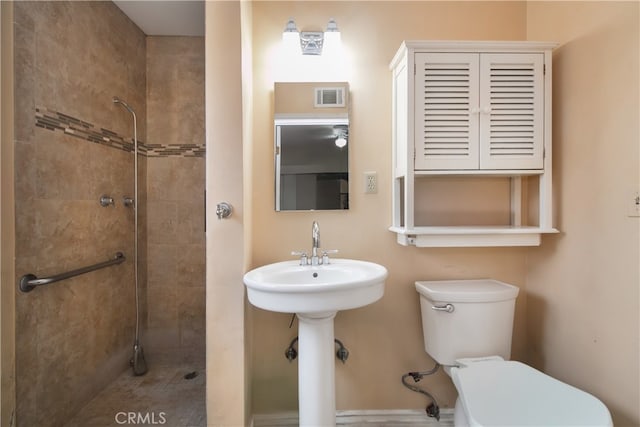 bathroom with a tile shower and toilet