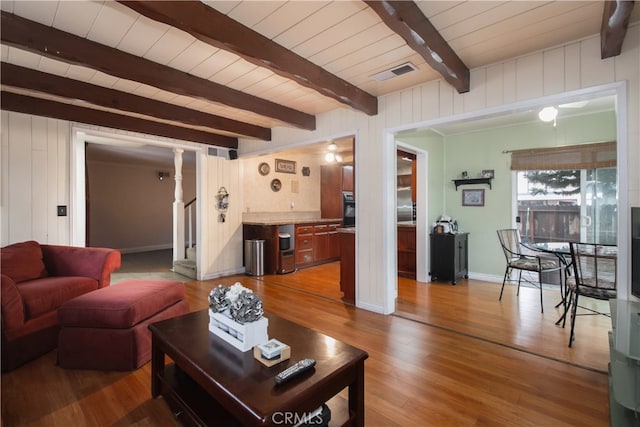 living room with wooden walls, hardwood / wood-style floors, wooden ceiling, and beam ceiling