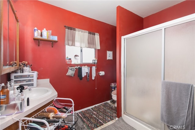 bathroom featuring toilet, vanity, and a shower with shower door