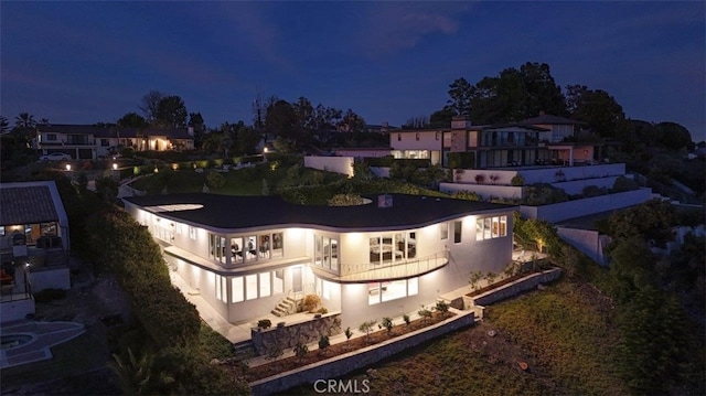 back of house at night with a balcony and stucco siding