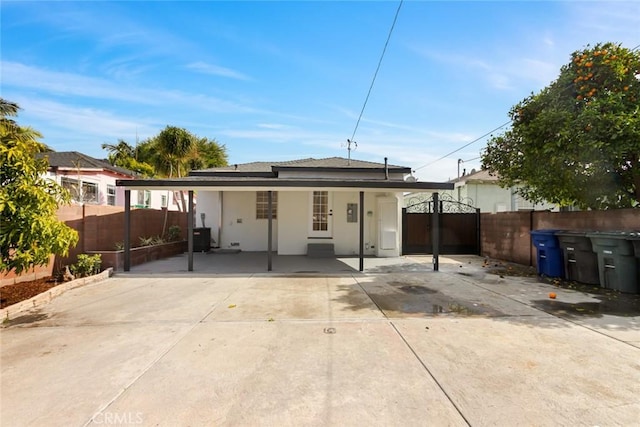 rear view of property featuring a gate, fence, and stucco siding