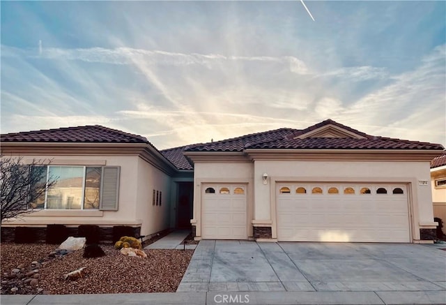 mediterranean / spanish-style house featuring concrete driveway, a tiled roof, an attached garage, and stucco siding