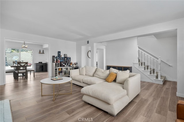 living area featuring baseboards, stairway, and wood finished floors