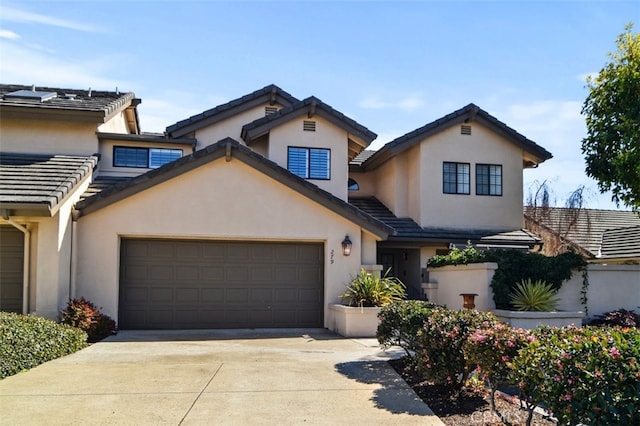 view of front of house featuring a garage, concrete driveway, a tile roof, and stucco siding