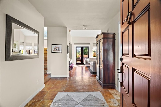 hall featuring stone finish floor, baseboards, visible vents, and french doors