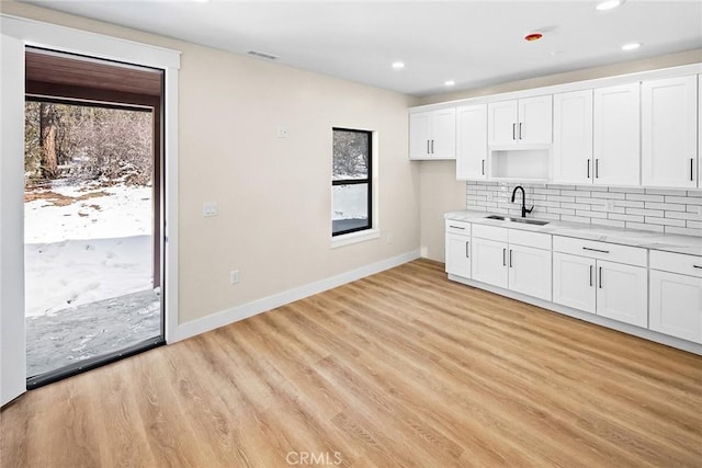 kitchen with sink, decorative backsplash, white cabinets, and light wood-type flooring