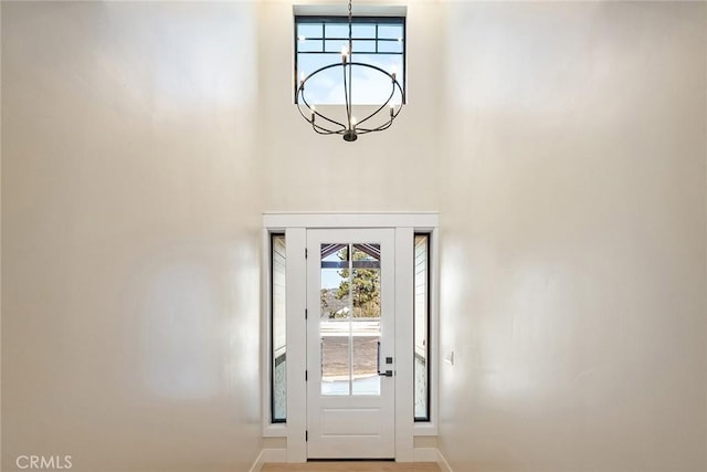 doorway to outside with an inviting chandelier and a high ceiling