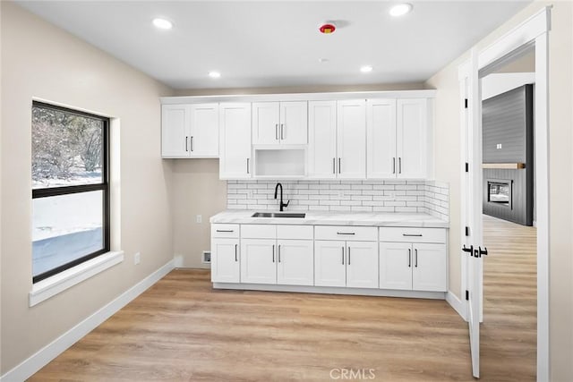 kitchen featuring white cabinetry, sink, decorative backsplash, and light wood-type flooring