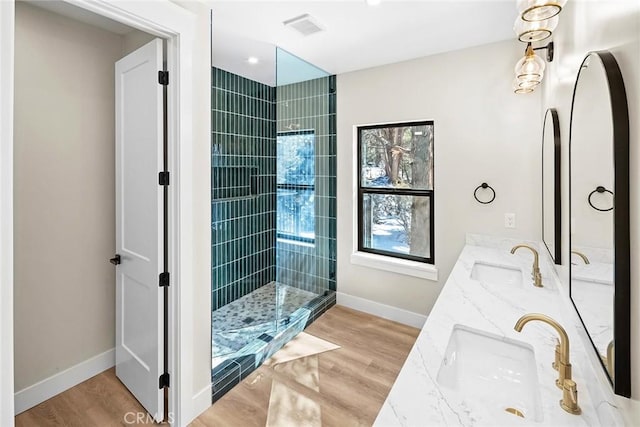 bathroom with vanity, wood-type flooring, and a tile shower