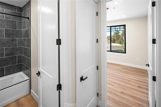 bathroom with hardwood / wood-style flooring and tiled shower / bath