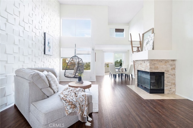 living room with a towering ceiling, wood-type flooring, and a fireplace