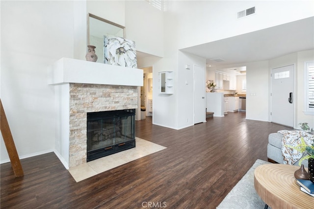 living room featuring dark hardwood / wood-style flooring, a towering ceiling, and a fireplace