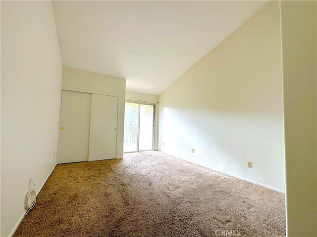 unfurnished bedroom featuring carpet, a closet, and lofted ceiling