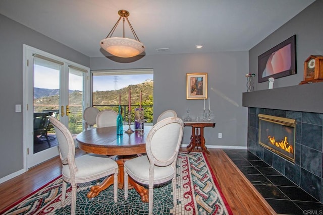 dining room with a tile fireplace, a mountain view, and dark hardwood / wood-style flooring