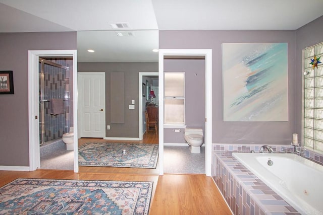 bathroom with hardwood / wood-style flooring, shower with separate bathtub, and toilet