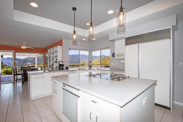 kitchen featuring white appliances, white cabinetry, a center island, a mountain view, and a raised ceiling