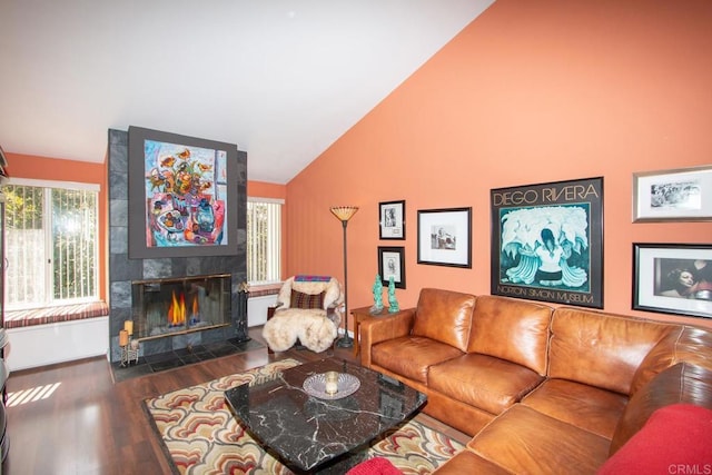 living room featuring dark hardwood / wood-style flooring, high vaulted ceiling, and a tile fireplace