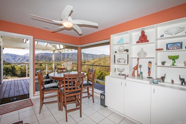 sunroom / solarium featuring ceiling fan, a healthy amount of sunlight, and a mountain view