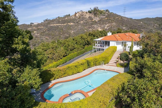 view of pool featuring an in ground hot tub, a mountain view, and a patio area