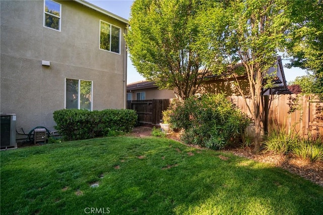 view of yard with a fenced backyard and central AC unit