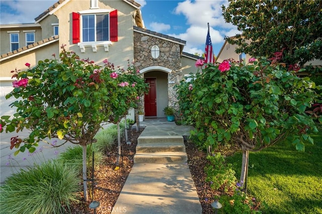 view of front of property with a garage, stone siding, and stucco siding