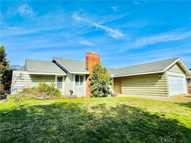 rear view of property with a garage and a lawn