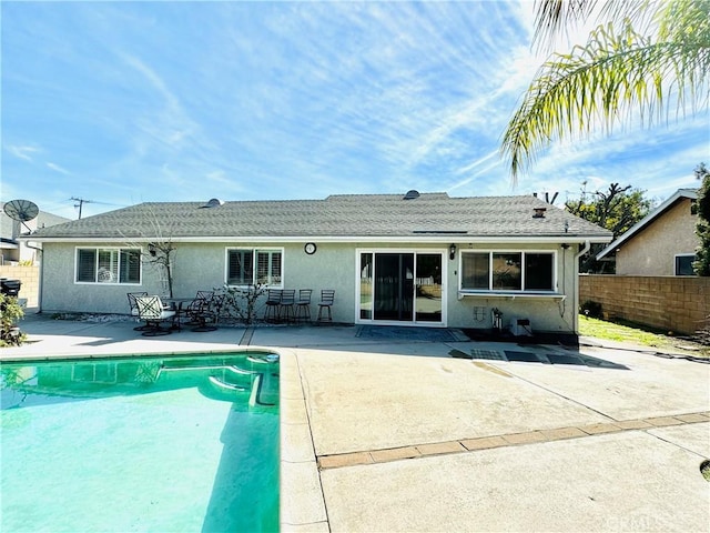 rear view of property featuring a fenced in pool and a patio