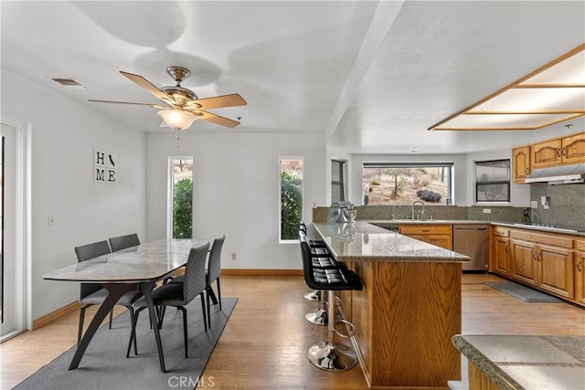 dining space with light wood-type flooring, sink, and ceiling fan