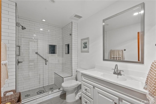 bathroom with toilet, vanity, and a shower with door