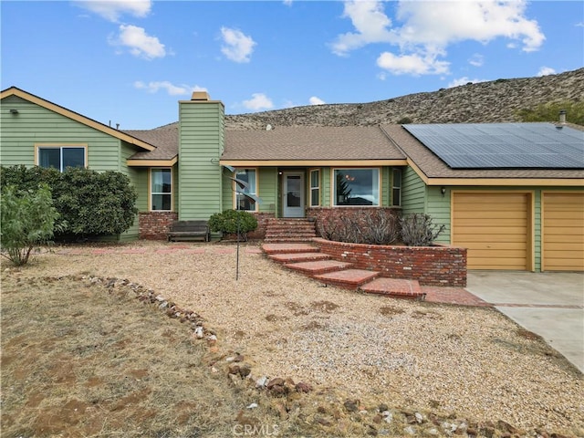 ranch-style house with a garage and solar panels