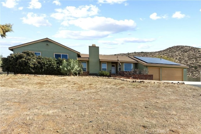 ranch-style home with a mountain view and solar panels