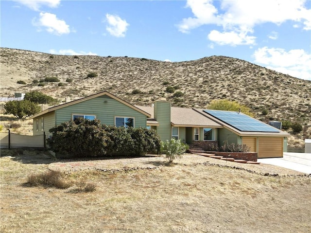 ranch-style home featuring a mountain view, solar panels, and a garage