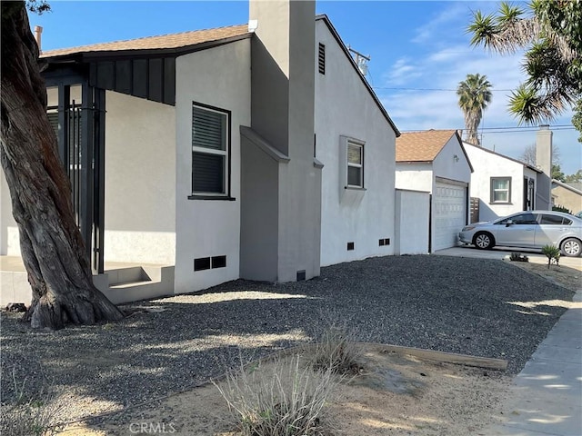 view of side of property featuring crawl space, a shingled roof, and stucco siding