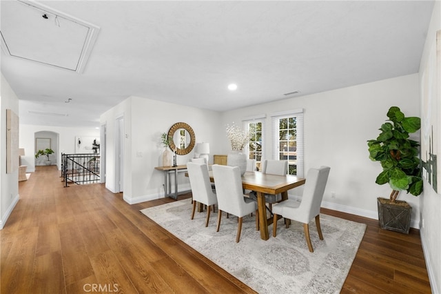 dining room with arched walkways, baseboards, and wood finished floors