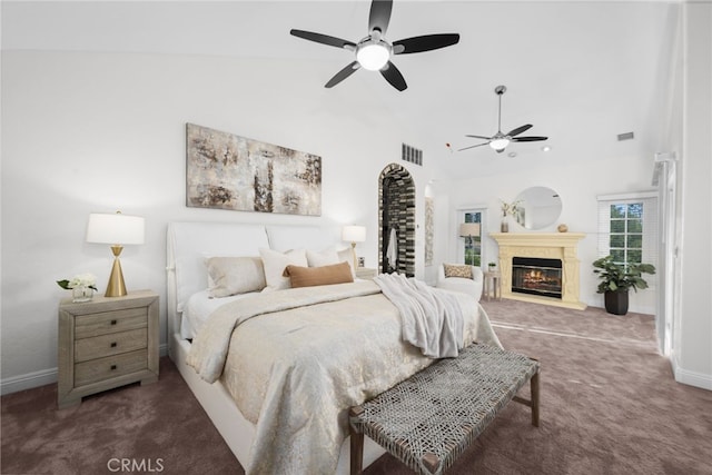 carpeted bedroom with ceiling fan, high vaulted ceiling, a glass covered fireplace, and visible vents