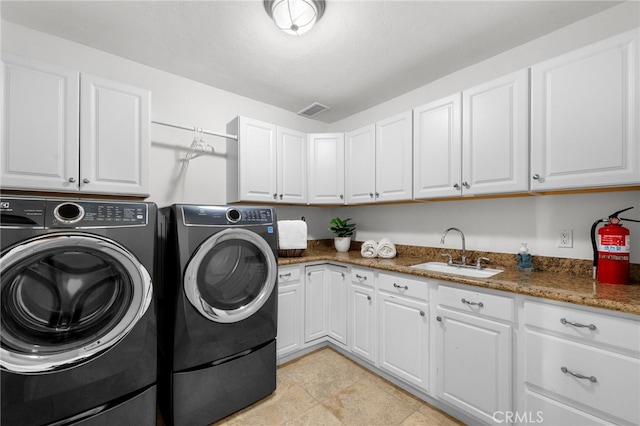 clothes washing area featuring washing machine and dryer, cabinet space, a sink, and visible vents