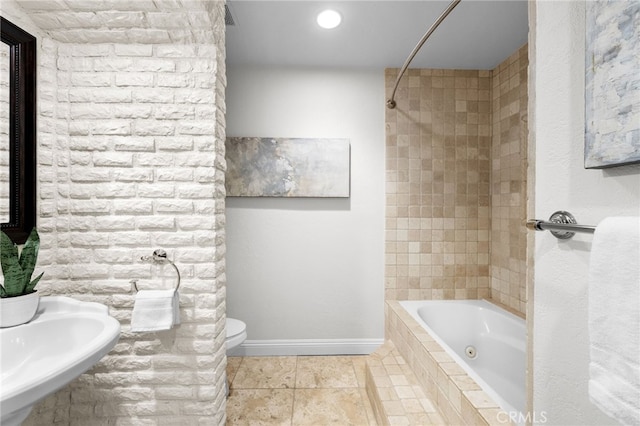 full bathroom featuring tile patterned flooring, toilet, tiled shower / bath combo, a sink, and baseboards