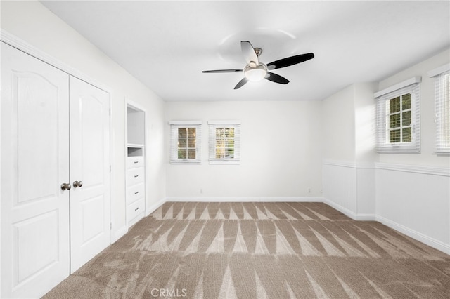 unfurnished bedroom featuring multiple windows, baseboards, and carpet flooring