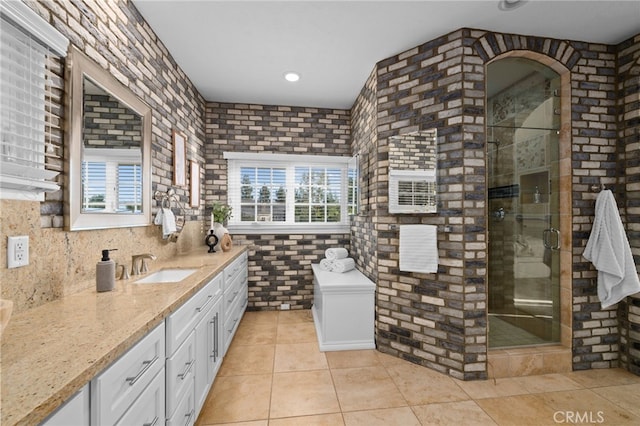 full bathroom with a stall shower, tile patterned flooring, brick wall, and vanity