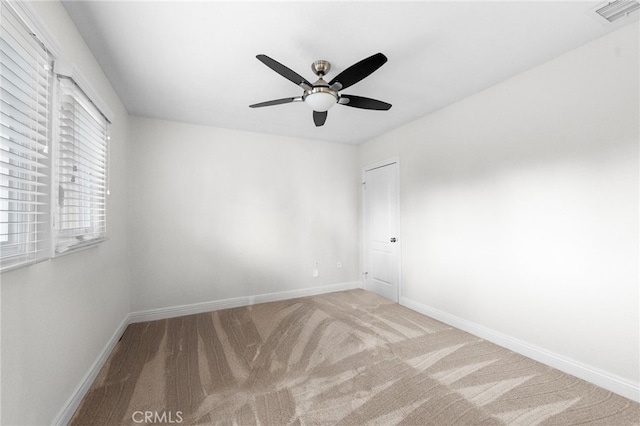 carpeted empty room with baseboards, visible vents, and ceiling fan