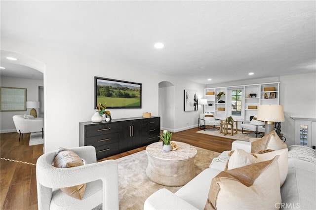 living room with arched walkways, baseboards, wood finished floors, and recessed lighting